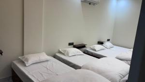 a room with four beds with white sheets and pillows at Hotel om namami in Rishīkesh