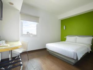 een slaapkamer met een wit bed en een groene muur bij Amaris Hotel La Codefin Kemang in Jakarta