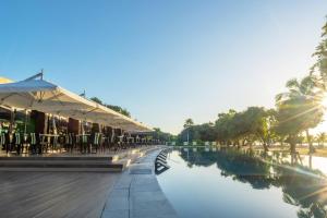 a pool of water with tables and chairs next to a resort at Astoria Palawan in Puerto Princesa City