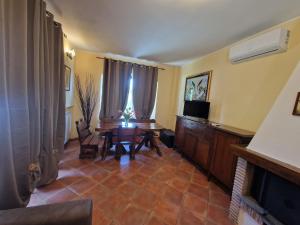 a living room with a table and a television at Villa Colle degli Ulivi con piscina e sguardo sul mare in Cerveteri