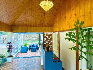 a living room with a wooden ceiling with a chandelier at Maharanee Bungalow Darjeeling in Darjeeling