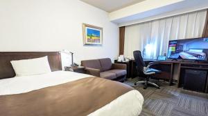 a hotel room with a bed and a desk with a computer at Hotel Sealuck Pal Takasaki in Takasaki