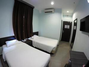 ein Hotelzimmer mit zwei Betten und einem Fernseher in der Unterkunft Hotel Bestari Prima in Kuala Lipis