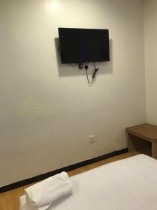 a bedroom with a bed with a flat screen tv on the wall at VIVA HOTEL SRI AMAN in Simanggang