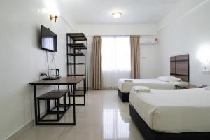 une chambre d'hôtel avec deux lits, un bureau et une télévision dans l'établissement Hotel Meligai Kapit, à Kapit