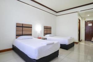 deux lits dans une chambre aux murs blancs dans l'établissement Hotel Meligai Kapit, à Kapit 165 autres photos