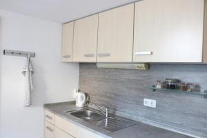 a kitchen with a sink and white cabinets at Ferienwohnung Weiss in Thyrnau in Thyrnau +6 photos