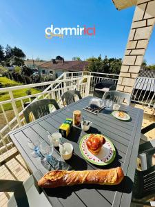 einen Tisch mit Essen und Brot auf dem Balkon in der Unterkunft SOLEIL LEVANT - Terrasse, clim, jardin & BBQ in Arvert