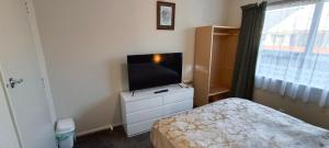 a bedroom with a television on a dresser with a bed at Charisma Homestay in Invercargill