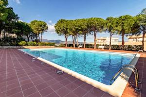 une piscine avec des arbres et un bâtiment en arrière-plan dans l'établissement Fener de Dalt 84 - apartamento piscina comunitaria, à Llançà