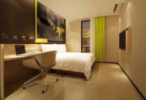 ein Schlafzimmer mit einem Bett und einem Schreibtisch mit einem Laptop in der Unterkunft IU Hotels·Xinyu City Government Xianlai Park in Xinyu