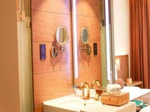 a bathroom with a sink and mirrors on a wall at James Joyce Coffetel Harbin Railway Station Songlei Yuanda Pedestrian Street in Harbin +70 photos