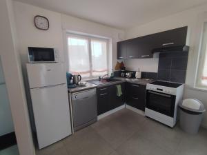 a kitchen with a white refrigerator and a stove at La Flandre entre campagne et littoral in Broxeele