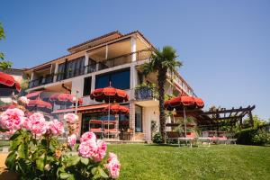 a building with red umbrellas and pink roses in front of it at Villa Bellevue Portoroz-Portorose in Portorož