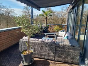 a patio with a couch and a tree on a balcony at Tolle Penthouse Wohnung direkt am Park in Heilbronn