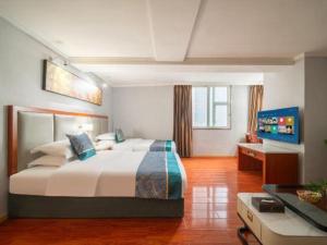 a bedroom with a large bed and a desk at Jun Hotel Guizhou Guiyang Yunyan District Yunyan Square in Guiyang