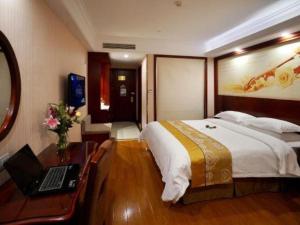 a bedroom with a bed and a desk with a laptop at GreenTree Inn Shanghai Waigaoqiao Free Trade Zone Express Hotel in Shanghai