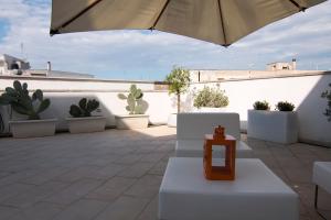 un patio con paredes blancas, cactus y sombrilla en Golden House, en Mesagne