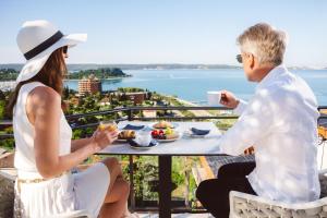 a man and woman sitting at a table with a cup of coffee at Villa Bellevue Portoroz-Portorose in Portorož