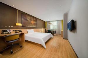 a bedroom with a bed and a desk and a television at IU Hotel Changsha Yuanjialing Metro Station 2nd Hospital of Xiangya in Changsha