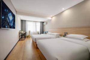 une rangée de lits blancs dans une chambre d'hôtel dans l'établissement Vatica Yangzhou Dongguan Street Hotel, à Yangzhou 177 autres photos