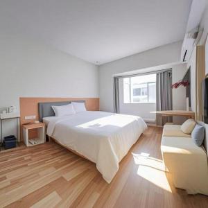 a white bedroom with a large bed and a couch at 7 Days Inn·Quanzhou Dehua Cidu Avenue in Dehua