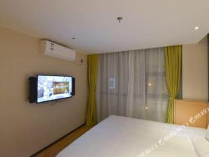 a bedroom with a bed and a tv on the wall at IU Hotel Anshun Zhenning Huangguoshu Scenic Area Toursit Center in Anshun