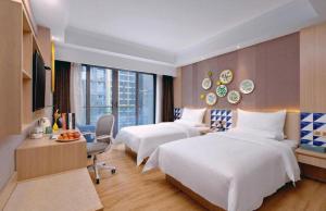 a hotel room with two beds and a desk at IU Hotel Guiyang Convention and Exhibition Center Financial City in Jinzhuzhen +192 photos