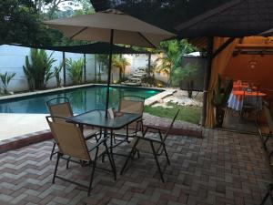 een tafel en stoelen met een parasol naast een zwembad bij Hostel Antorchas in Dominical