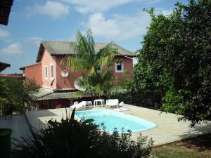 a house with a swimming pool in front of a house at Pousada Pimenta Rosa in Saquarema