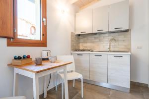 a kitchen with white cabinets and a wooden table at Villa Campidanese in Assemini +32 photos