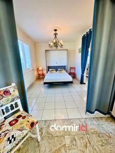 ein Schlafzimmer mit einem Bett und Stühlen in einem Zimmer in der Unterkunft SOLEIL LEVANT - Terrasse, clim, jardin & BBQ in Arvert