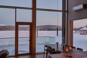 a dining room with a table and a large window at Stay North - The House of Northern Lights in Äkäslompolo