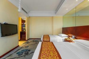 a hotel room with two beds and a flat screen tv at Nanchang Oriscene Garden Hotel in Nanchang