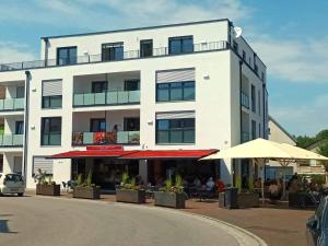 a white building with tables and umbrellas in front of it at Hotel und Ferienwohnungen Nebauer in Frontenhausen