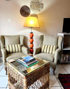 a living room with two chairs and a table with a lamp at Studio 28 Clarens Apartment B in Clarens