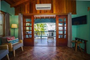 a living room with a door open to a balcony at Toucan Dance Villa - 3BR Beachfront wPool Ocean Views in Maya Beach