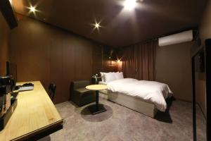 a bedroom with a bed and a table and a desk at Hotel Moon in Anyang