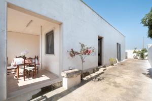 une maison blanche avec une table et des chaises sur la terrasse couverte dans l'établissement Villa Respiro Azzurro, à Porto Cesareo