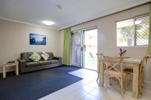 a living room with a couch and a table at Beachpark Apartments Coffs Harbour in Coffs Harbour