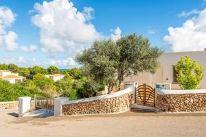 a house with a stone fence and a tree at Villa Rachel in Es Mercadal