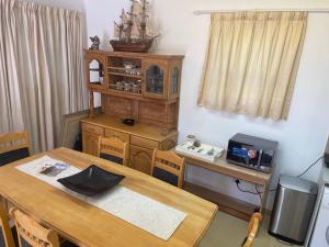 a dining room with a wooden table and a desk with at Knysna's Rest in Brenton-on-Sea