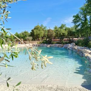 a swimming pool with blue water and rocks at Camping Liberté Verdon in Artignosc-sur-Verdon