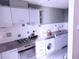 a kitchen with white cabinets and a washing machine at Luxury 2Bed Room Riverview Apartment in Greenwich