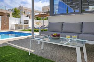 un soggiorno con divano e tavolo accanto alla piscina di Villa Violeta - 3bed Bungalow large pool a Protaras Altre 23 foto