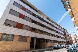 un grand bâtiment avec des voitures garées devant dans l'établissement Apartamento en Delicias 'Hector' - Parking Incluido, à Saragosse