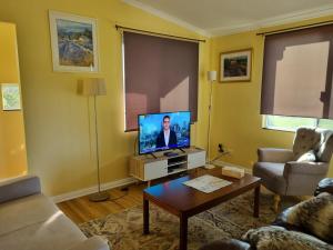 a living room with a tv and a table at Lavender Cottage at Nannup Lavender Farm in Nannup