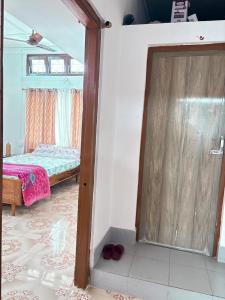 Cette chambre comprend un lit et une porte menant à une chambre. dans l'établissement Maadhuban Home Stay, à Dibrugarh 1 autre photo