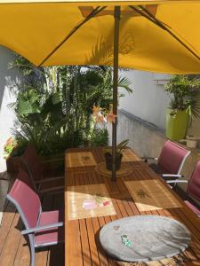drewniany stół z żółtym parasolem na pokładzie w obiekcie P'ti caze w mieście Saint-Gilles les Bains +8 zdjęć