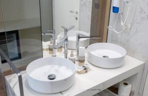 a bathroom with two white sinks on a counter at Empire Beach Resort ADULTS ONLY in Dhërmi